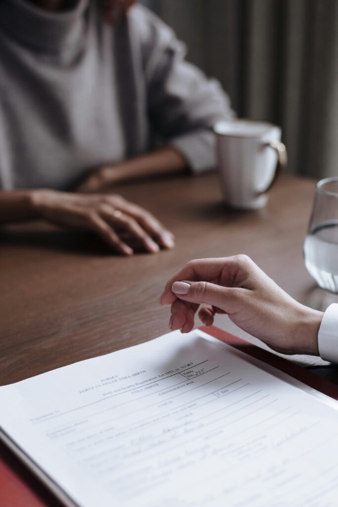 Two people in a business meeting reviewing and signing a contract.